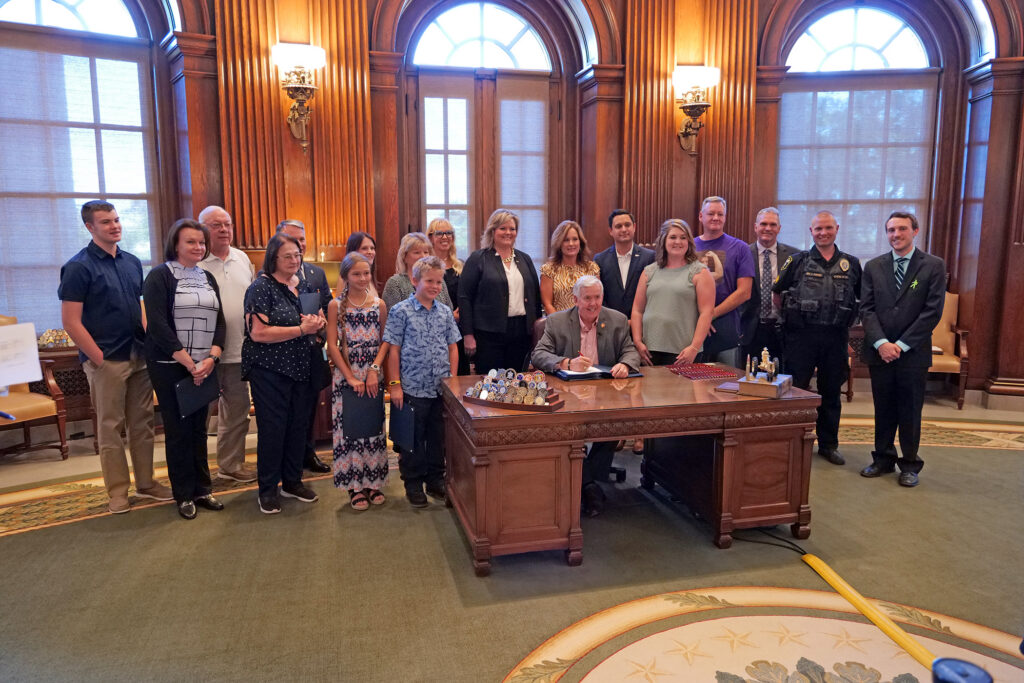 People gathered around a desk for the signing of a law. 