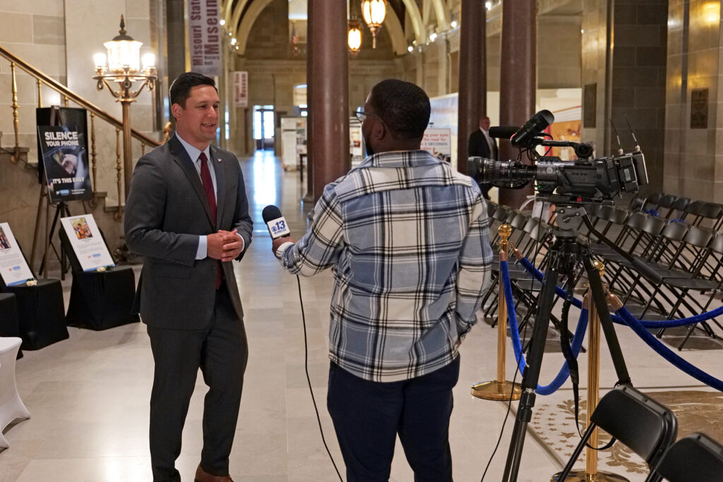 A man in a suit speaking to a member of the press