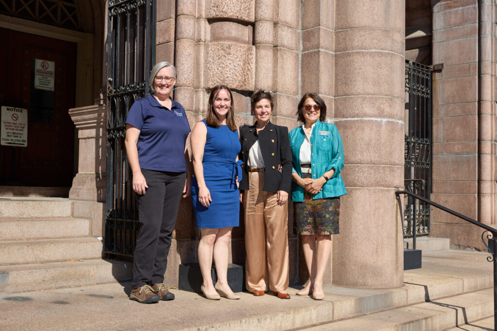 Four women pose for a photo in front of St. Louis City Hall. From left to right are Jen Wade, MODOT Area Engineer; Sarah Arnosky Ko, Vice President of Greater St. Louis Inc; Cara Spencer, Mayor of the City of St. Louis; and Cindy Mense, CEO of Trailnet